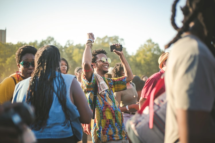 Picture of guy at festival with his hands up. 