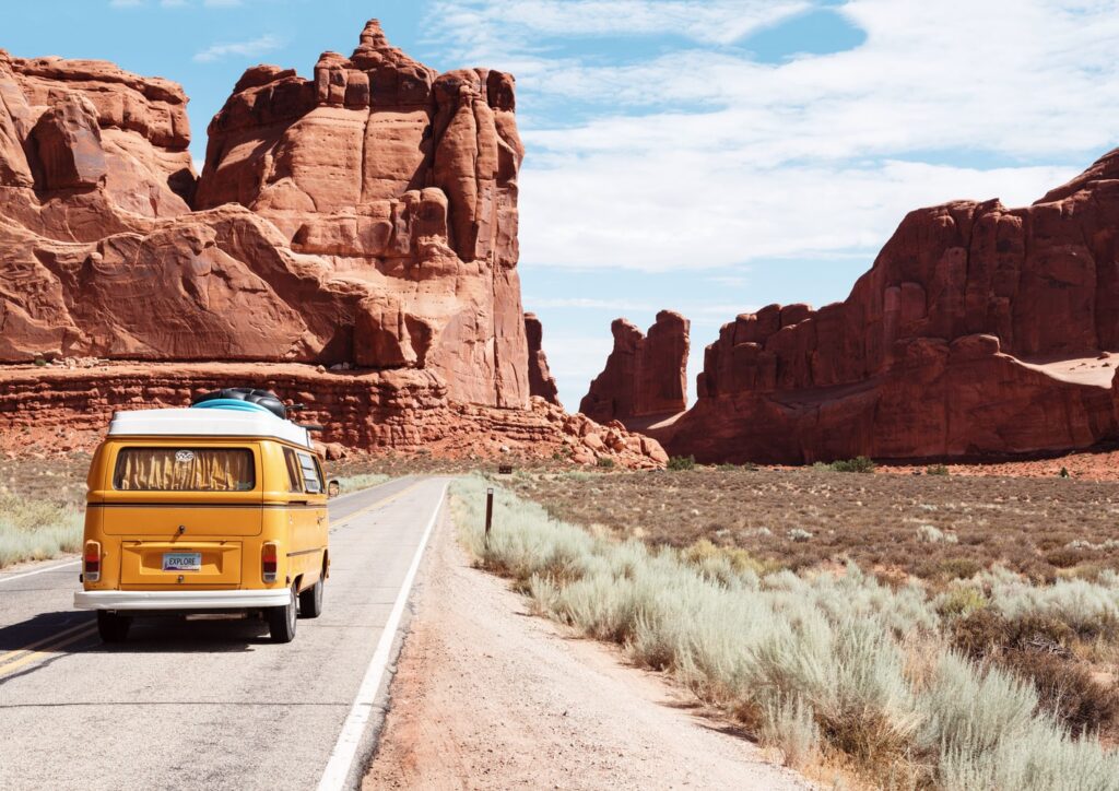 Picture of volkswagon bus in desert with big rocks.