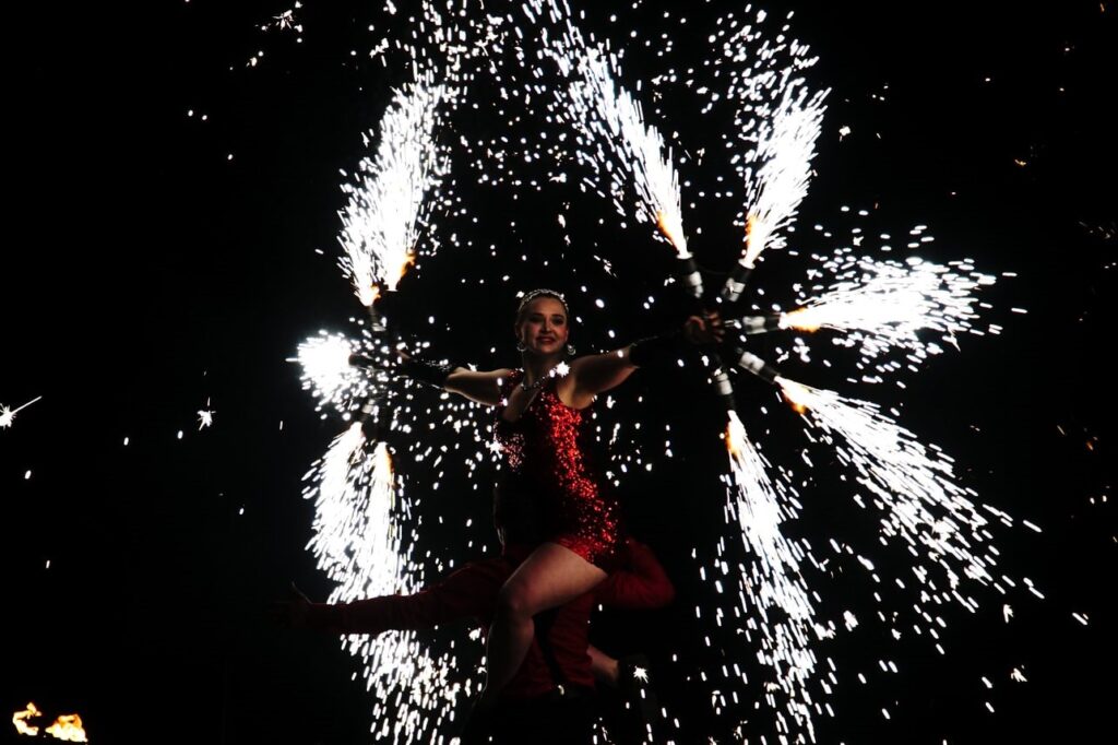 Woman on man's shoulders with sparklers. 