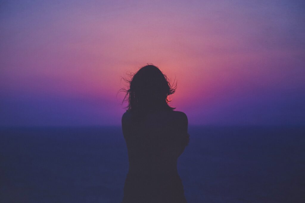 Silhouette of girl on purple and red sunset.